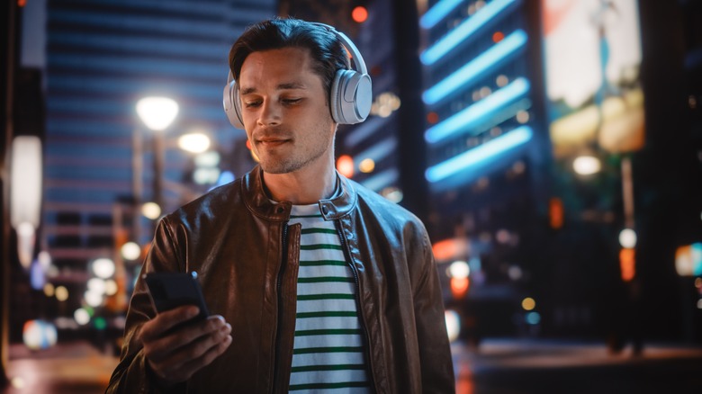 Man in city wearing headphones at night